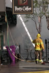 Firefighter Hollomon with the Long Beach Fire Department heads for a ladder to access the roof of the Bar & Grill. (62kb)