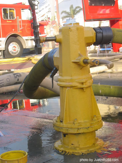 This yellow fire hydrant gets wet from the fire department this sunny morning, instead of from its usual four-legged visitors.