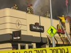 Fireman atop Peet's Coffee and O' My Sole, the businesses next door to the burning business. (49kb)